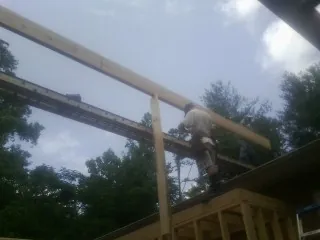 Carpenter setting a ridge beam over a new addition frame — Ice Dam Removal by Roofing Brothers in Himrod