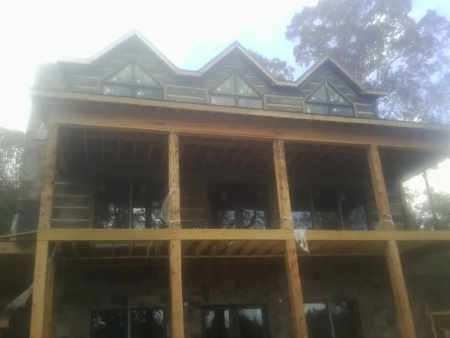Dormers and porch framing on a large log home under construction — Roof Coating work by our crew in Himrod