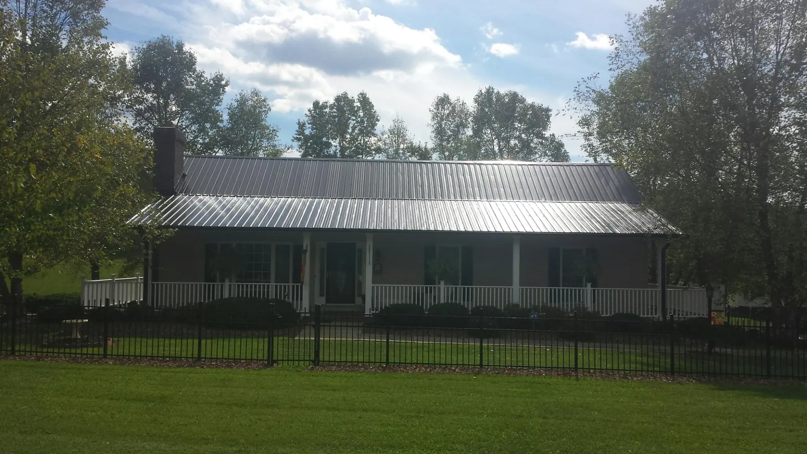 Gray metal roof on a brick ranch with a full width front porch — Gutter Guard Installation work by our crew in Himrod