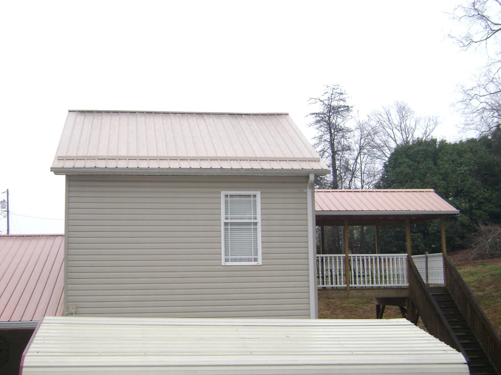 Tan metal roofs on a two story addition and attached porch, from a Roof Replacement job in Himrod