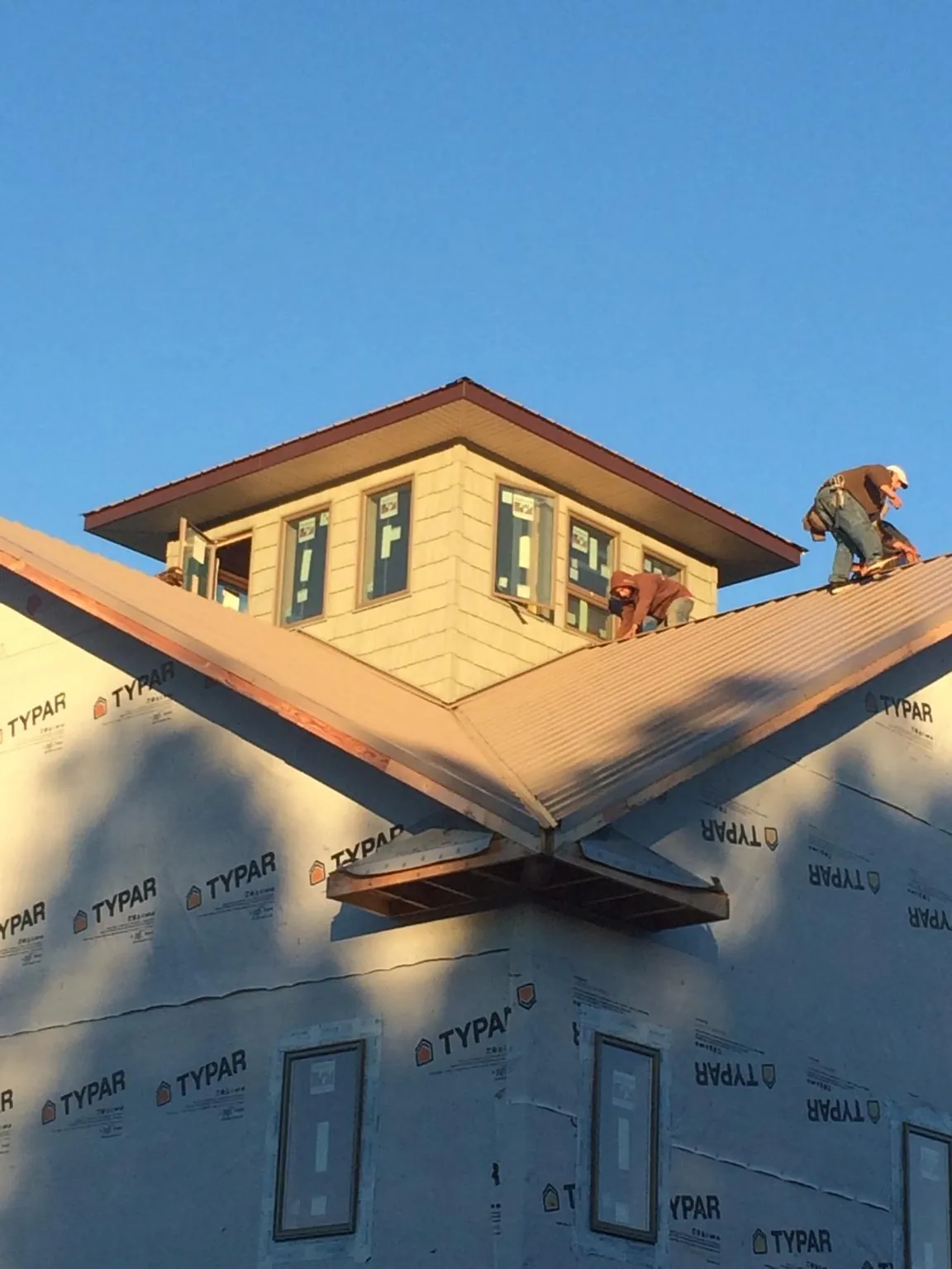 Roofers working around a rooftop cupola on a new metal roof at sunset — Roof Waterproofing in Himrod by Roofing Brothers